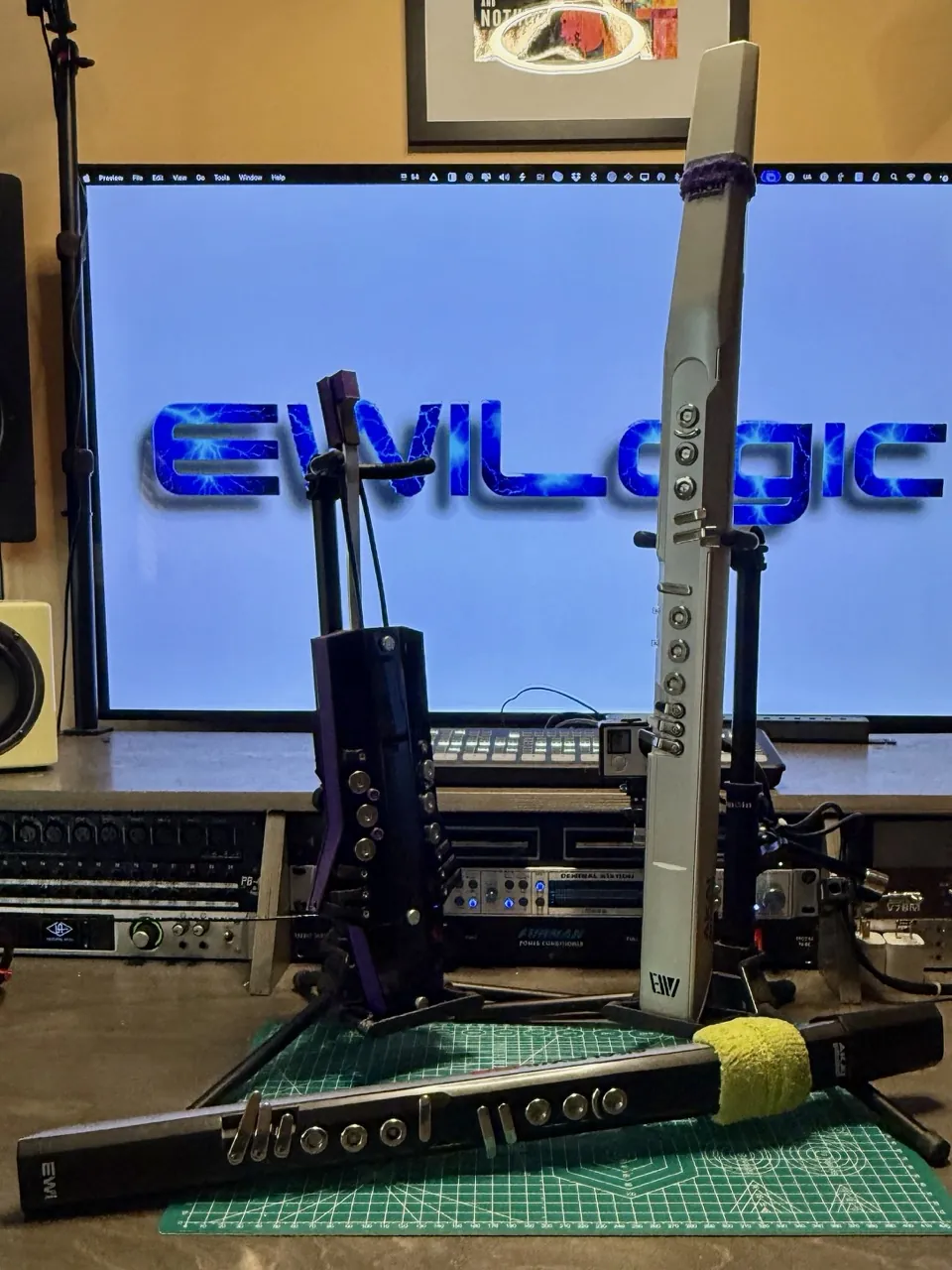 The EWIs on stands in front of a large screen showing the EWILogic logo.