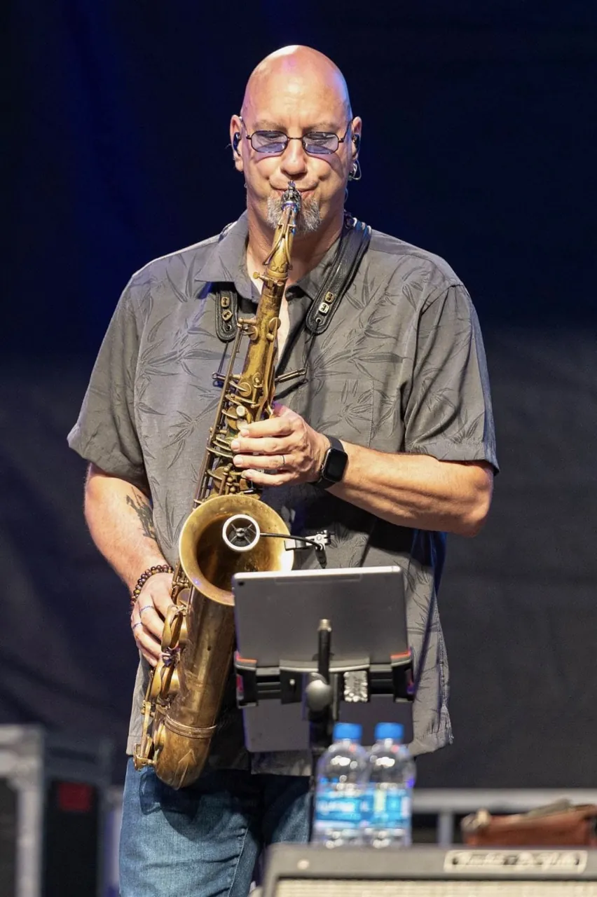 John playing saxophone on a festival stage.